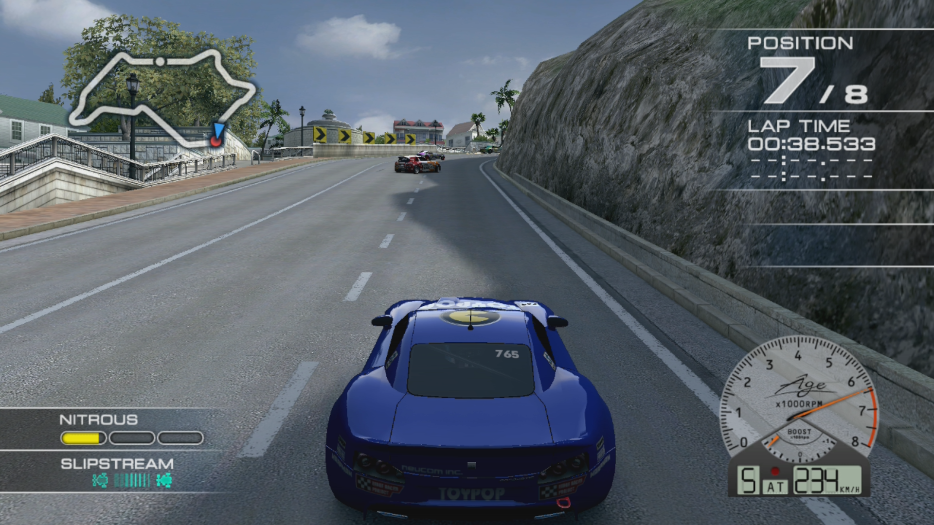 A blue car approaching a tight bend in Ridge Racer 7.