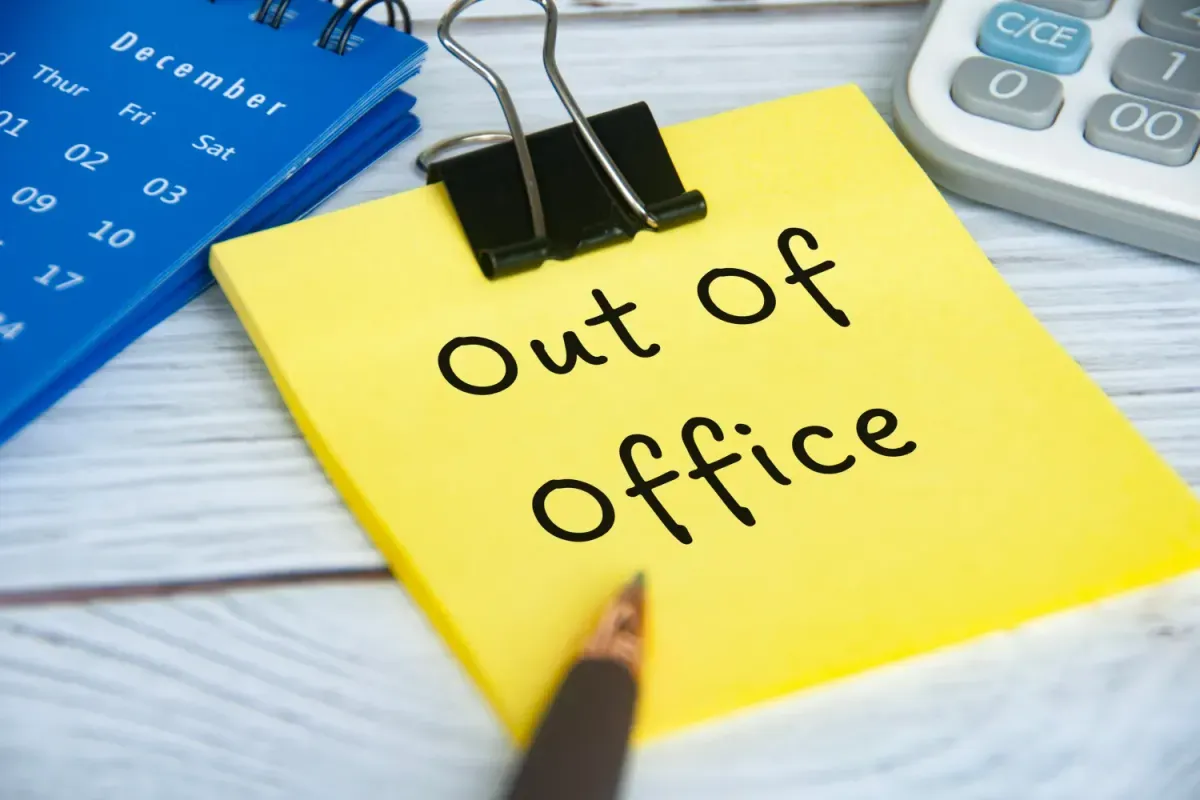 An "Out of Oficce" post-it note on a desk.